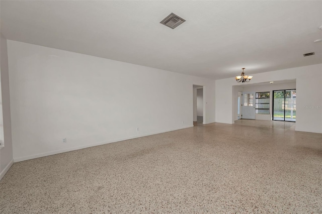 spare room featuring baseboards, speckled floor, visible vents, and a notable chandelier