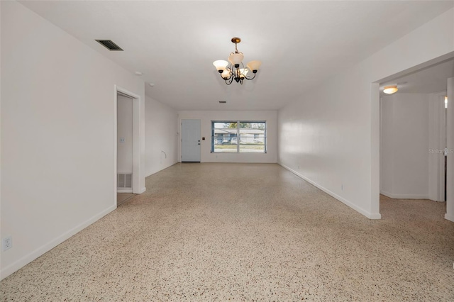 spare room featuring a chandelier, visible vents, baseboards, and speckled floor