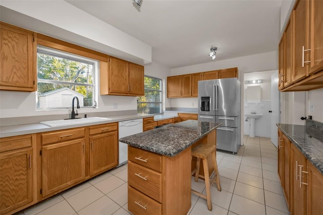 kitchen with a breakfast bar, light tile patterned floors, a sink, white dishwasher, and stainless steel fridge with ice dispenser