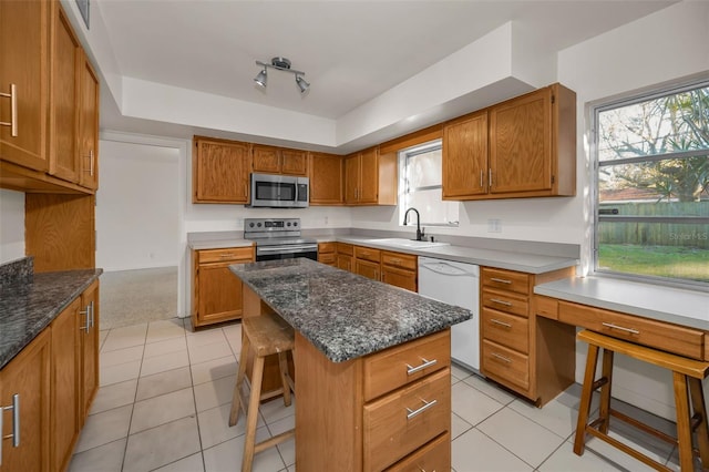 kitchen with stainless steel appliances, brown cabinets, a sink, and a breakfast bar area