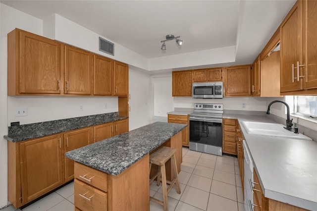 kitchen with visible vents, a raised ceiling, a kitchen island, stainless steel appliances, and a sink