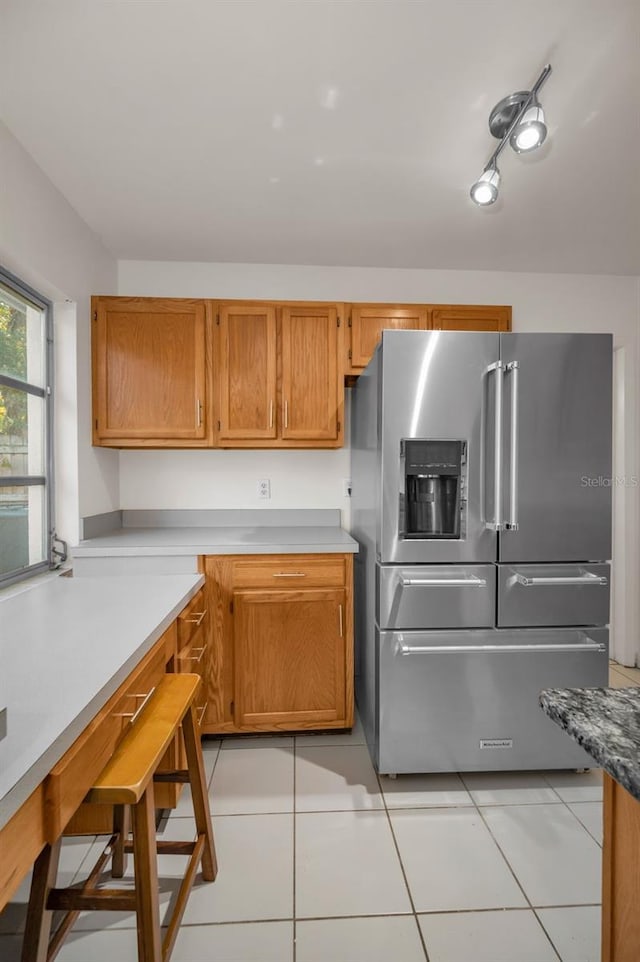 kitchen with high quality fridge, brown cabinets, and light tile patterned flooring