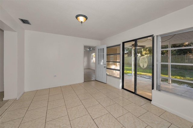 empty room with light tile patterned floors, ceiling fan, and visible vents