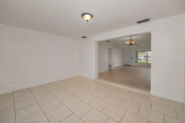 unfurnished room featuring visible vents and a notable chandelier