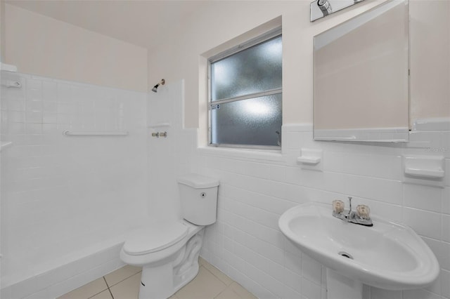 full bathroom with a wainscoted wall, toilet, a sink, tile patterned flooring, and walk in shower