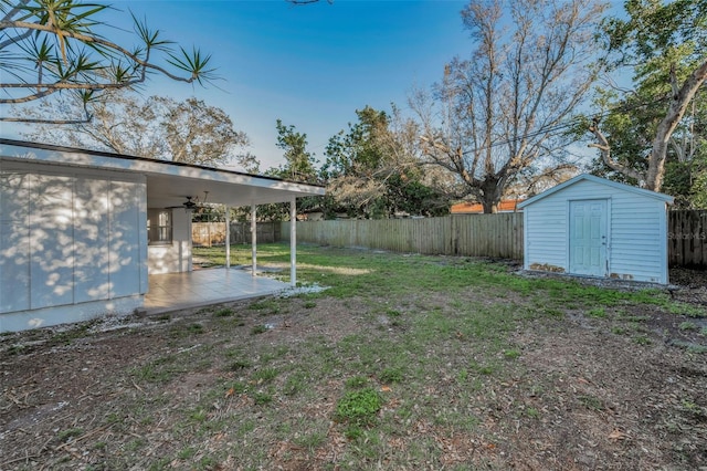 view of yard with an outbuilding, a storage shed, a patio area, ceiling fan, and a fenced backyard