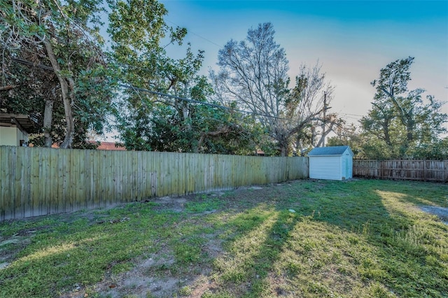 view of yard featuring a storage shed, a fenced backyard, and an outdoor structure