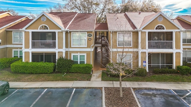 view of property featuring uncovered parking and stairs