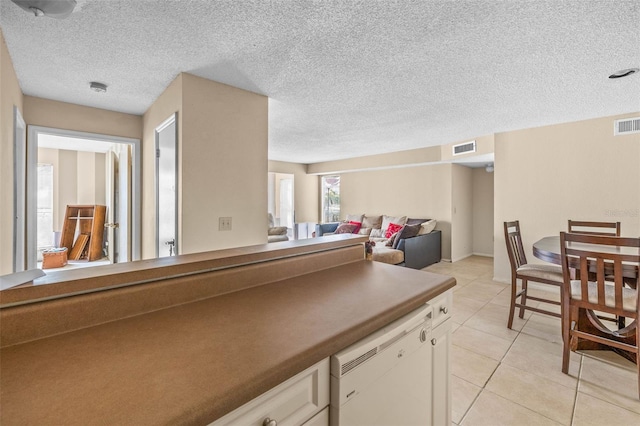 kitchen featuring light tile patterned floors, white cabinetry, visible vents, and dishwasher