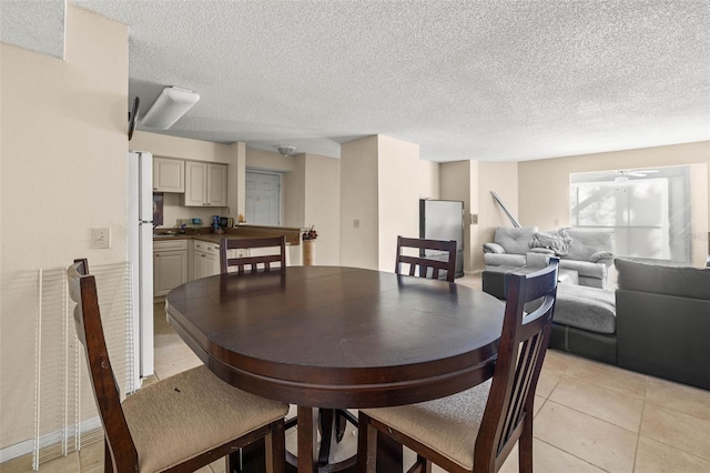 dining area featuring a ceiling fan, light tile patterned flooring, and a textured ceiling