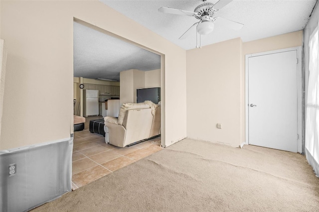 unfurnished living room featuring tile patterned flooring, carpet, ceiling fan, and a textured ceiling