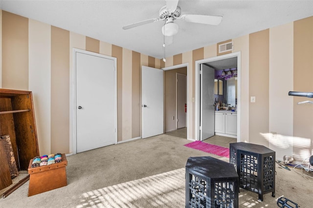 interior space with carpet floors, a ceiling fan, visible vents, and wallpapered walls