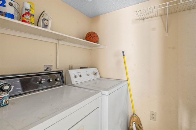 washroom with a textured ceiling, laundry area, and washing machine and dryer