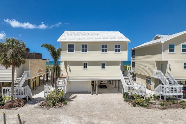 back of house featuring a garage, driveway, a carport, and stairs