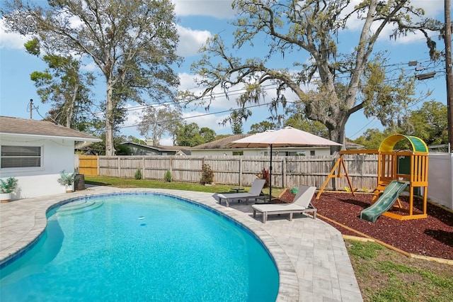 view of pool with a patio, a playground, a fenced backyard, and a fenced in pool