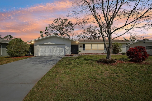 ranch-style house featuring stucco siding, a lawn, a garage, and driveway