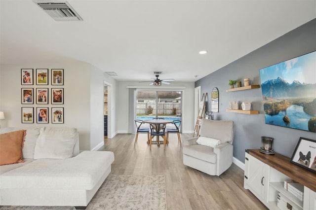 living room featuring visible vents, baseboards, and light wood finished floors