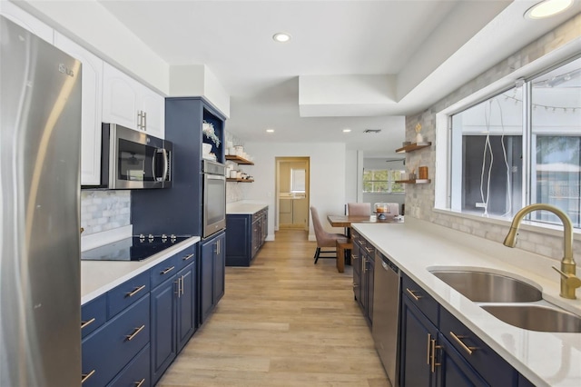 kitchen featuring open shelves, blue cabinetry, appliances with stainless steel finishes, and a sink