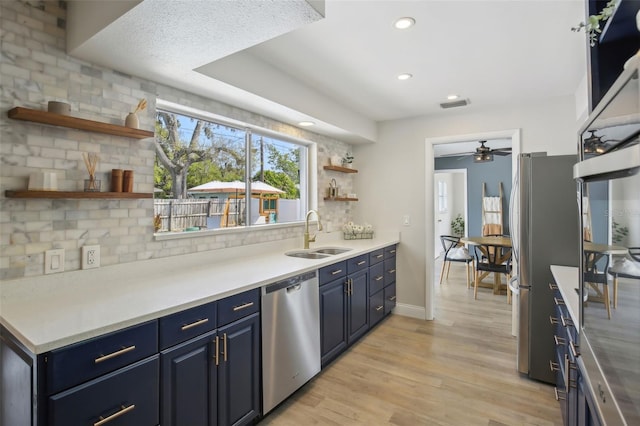 kitchen featuring backsplash, blue cabinetry, open shelves, stainless steel appliances, and a sink