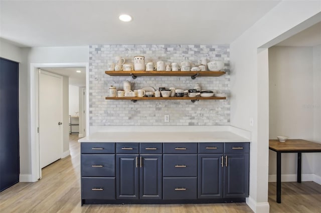 bar with light wood finished floors, decorative backsplash, and baseboards