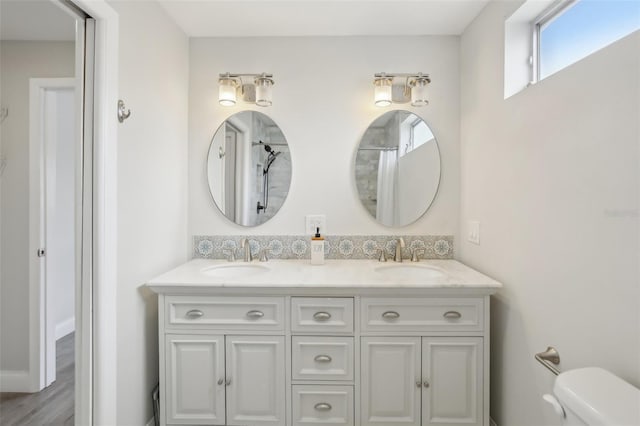 bathroom with double vanity, curtained shower, toilet, and a sink