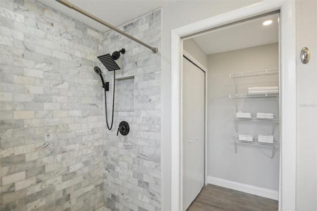 bathroom featuring wood finished floors, baseboards, and tiled shower