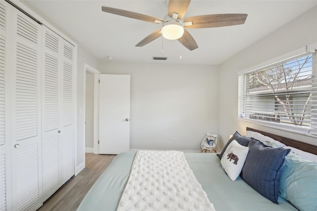 bedroom featuring wood finished floors, baseboards, visible vents, ceiling fan, and a closet