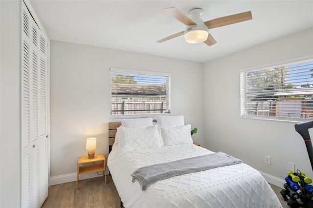 bedroom with a closet, baseboards, wood finished floors, and a ceiling fan