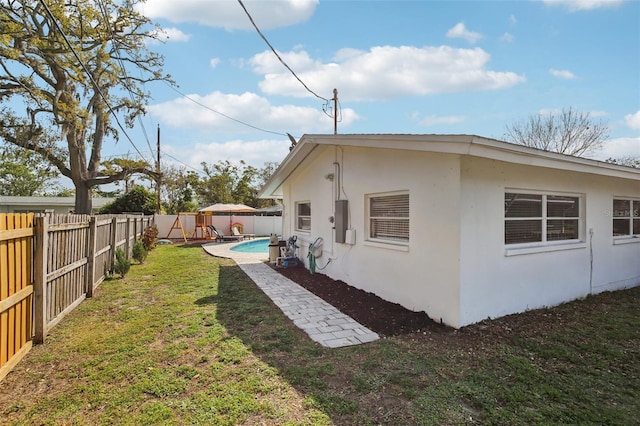 view of side of home featuring a fenced in pool, a yard, a fenced backyard, stucco siding, and a playground