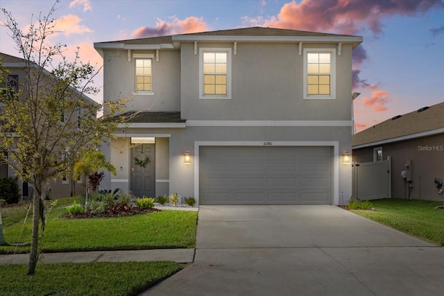 traditional-style home with a garage, driveway, fence, and stucco siding