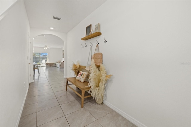 hallway with arched walkways, light tile patterned floors, visible vents, and baseboards