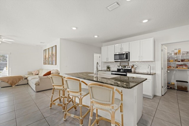 kitchen with light tile patterned floors, visible vents, stainless steel appliances, a kitchen bar, and a sink