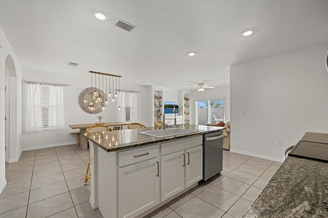 kitchen with arched walkways, visible vents, stainless steel dishwasher, and light tile patterned floors