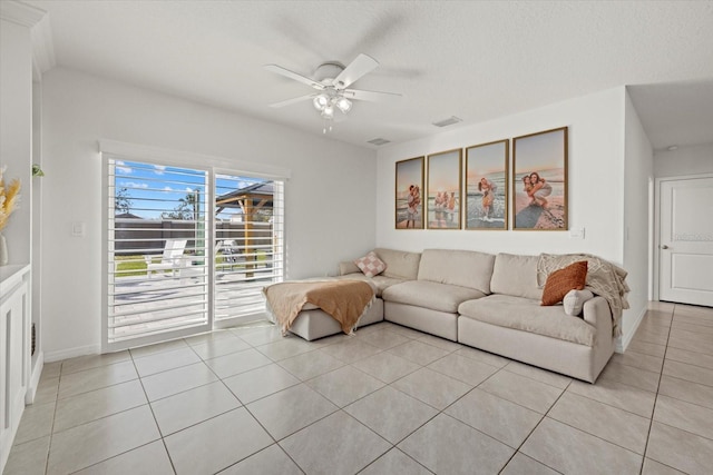 living room featuring light tile patterned floors, baseboards, visible vents, a ceiling fan, and a textured ceiling