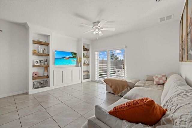 living room with a textured ceiling, light tile patterned floors, a ceiling fan, visible vents, and built in features