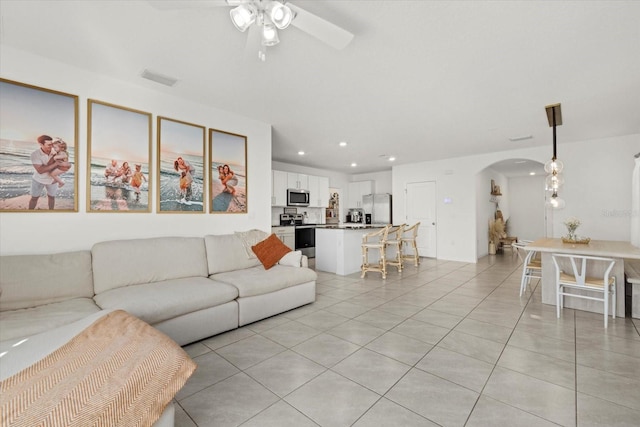 living area featuring visible vents, arched walkways, ceiling fan, light tile patterned flooring, and recessed lighting