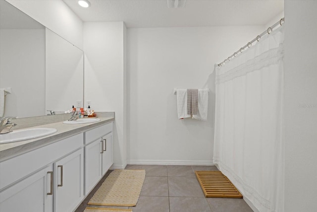 full bathroom with tile patterned flooring, a sink, baseboards, and double vanity