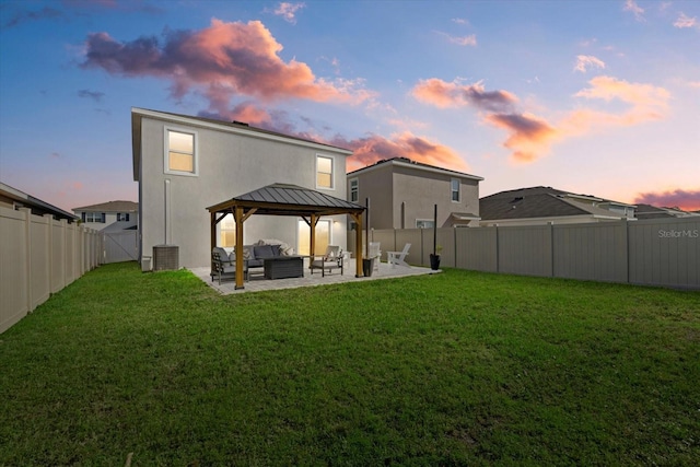 back of property at dusk featuring a standing seam roof, a gazebo, a patio, and a lawn