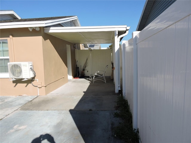 view of patio featuring ac unit, fence, and a carport