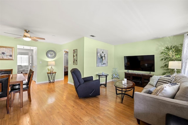 living room with visible vents, ceiling fan, light wood-style flooring, and baseboards