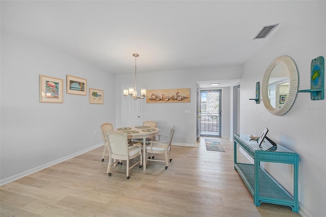 dining space with visible vents, baseboards, light wood-type flooring, and an inviting chandelier