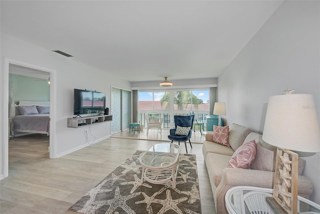 living room featuring visible vents, baseboards, and wood finished floors