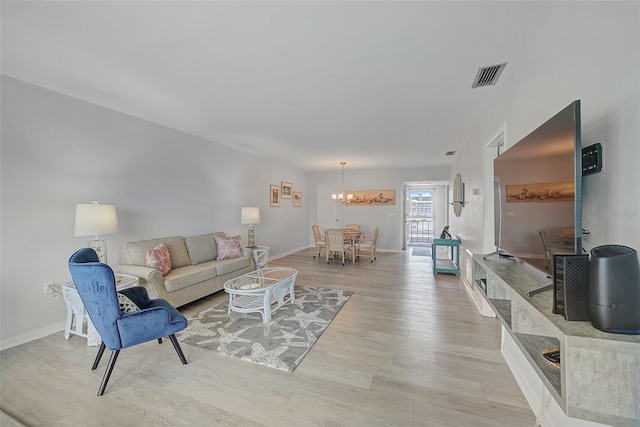 living room featuring an inviting chandelier, visible vents, light wood-type flooring, and baseboards