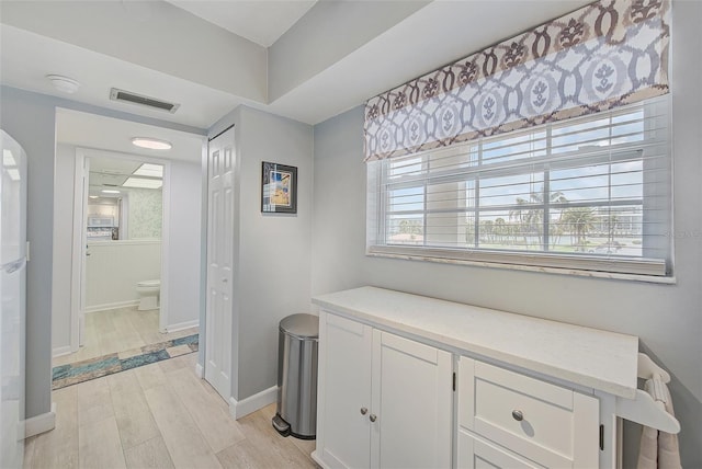 corridor with visible vents, baseboards, and light wood-style floors