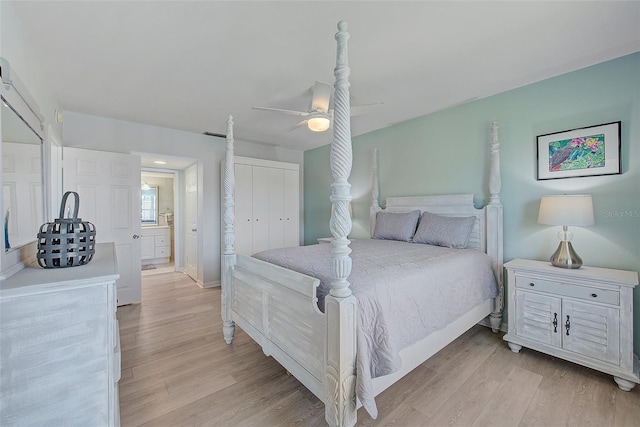 bedroom featuring light wood-type flooring, a ceiling fan, ensuite bath, a closet, and baseboards