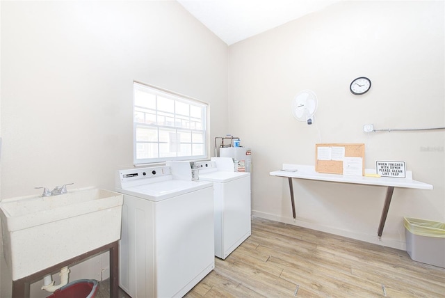 laundry area with light wood-type flooring, independent washer and dryer, a sink, water heater, and laundry area