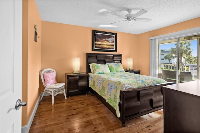 bedroom with access to exterior, a textured ceiling, baseboards, and wood finished floors