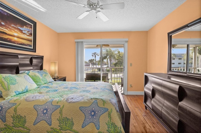 bedroom with access to exterior, multiple windows, wood finished floors, and a textured ceiling