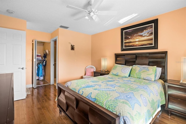 bedroom with visible vents, a walk in closet, a ceiling fan, wood finished floors, and a closet