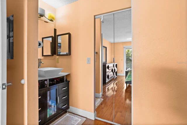 bathroom with a textured ceiling, vanity, baseboards, and hardwood / wood-style flooring